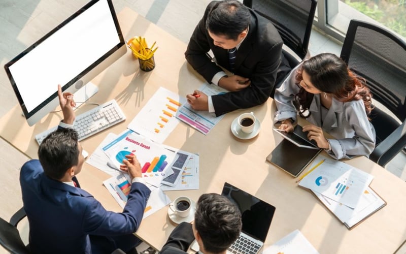 Coworkers sitting at a table looking at computer screen