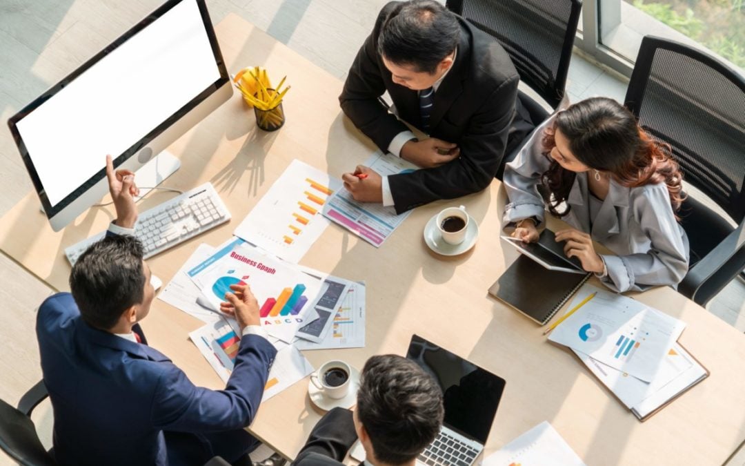 Coworkers sitting at table looking at computer screen