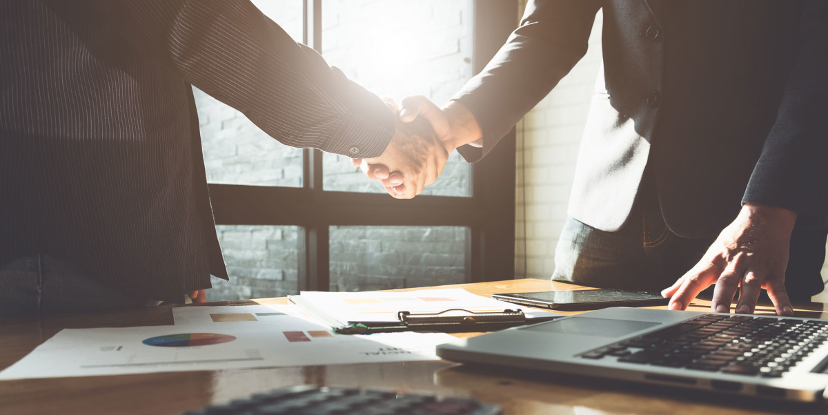 Two people shaking hands over a desk