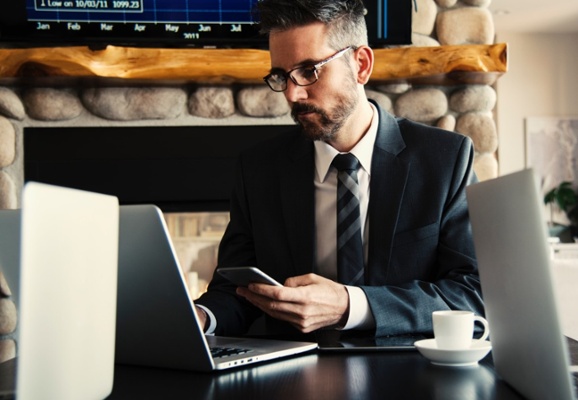 Man in suit working on phone and laptop